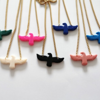 Colares com pendentes de aves coloridas em correntes douradas sobre fundo branco