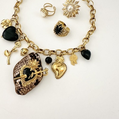 Pulseira dourada com elos e pendentes diversos e três anéis dourados com pedras pretas e pérolas