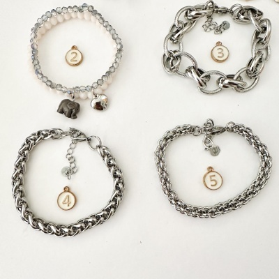 Quatro pulseiras em metal prateado e contas, numeradas, sobre fundo branco