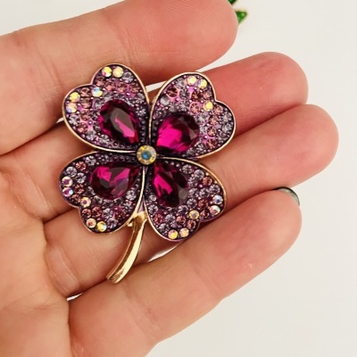 Broche trevo com pedras rosas e roxas, moldura dourada