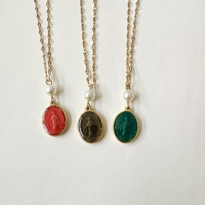 Três colares com medalhões coloridos e pérolas sobre fundo branco