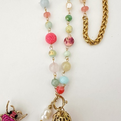 Colar com contas coloridas e corrente dourada sobre fundo branco