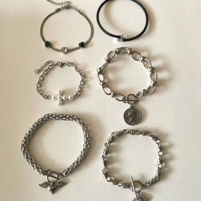 Conjunto de seis pulseiras em metal prateado e borracha preta com diferentes estilos e detalhes