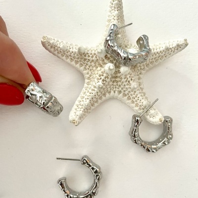 Brincos argola prateados com textura bambu sobre estrela-do-mar branca