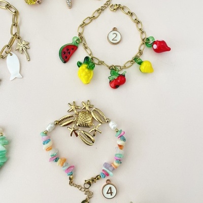 Pulseiras e brincos coloridos de frutas e conchas sobre fundo branco