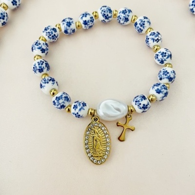 Pulseira com contas brancas e azuis, pendentes dourados, cruz e medalha religiosa