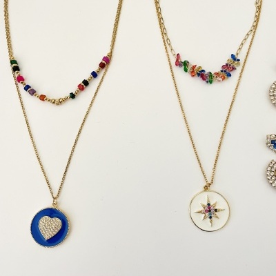 Dois colares dourados com pendentes coloridos e correntes decorativas em fundo branco