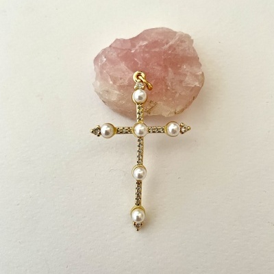 Pendente em cruz dourada com pérolas sobre pedra rosa