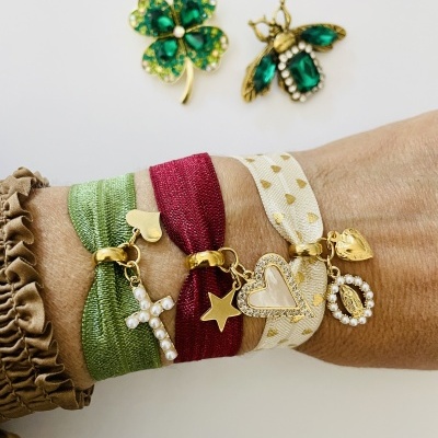 Braceletes coloridos com pendentes dourados e broches verdes em fundo branco