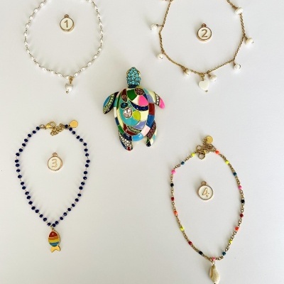 Quatro pulseiras numeradas e pendente de tartaruga colorido ao centro