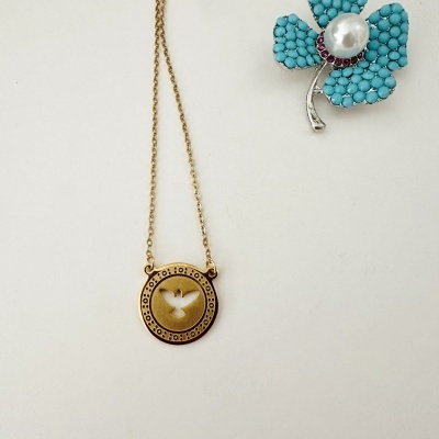 Colar dourado com pendente redondo e flor azul decorativa ao lado