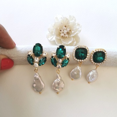 Dois pares de brincos com pedras verdes e pérolas sobre suporte branco