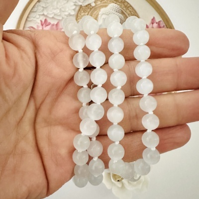 Quatro fios de pérolas brancas translúcidas redondas numa mão