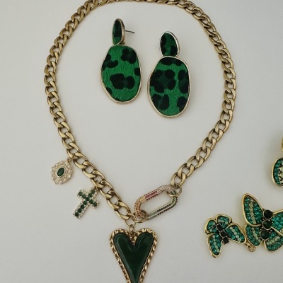 Colar dourado com pendentes e brincos verdes sobre fundo branco