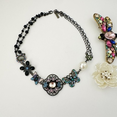 Colar com borboletas decoradas e pedras, broche de insecto colorido e flor branca com pérolas.