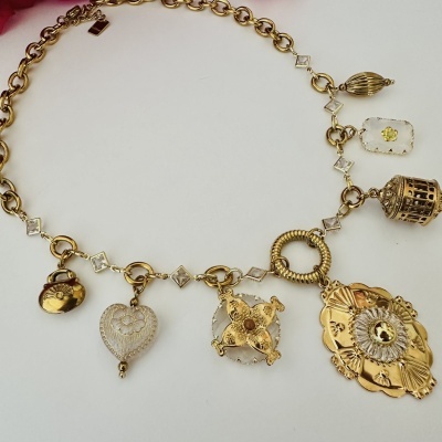 Colar dourado com múltiplos pendentes decorativos sobre fundo branco