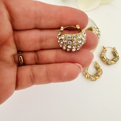 Brincos dourados com pedras brilhantes em fundo branco