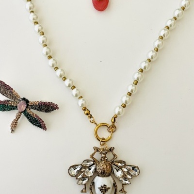 Colar com pendente abelha e broche libélula sobre fundo branco