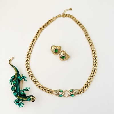 Conjunto de joias douradas com pedras verdes e broche de lagarto verde