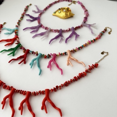 Bijuterias coloridas com elementos em forma de coral e pendente de concha dourada