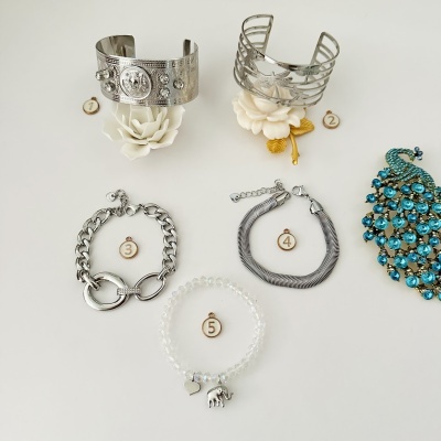 Cinco pulseiras e um broche azul com pedras sobre fundo branco numerados