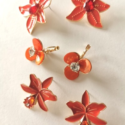 Brincos em forma de flores cor laranja com detalhes dourados e pedras brilhantes