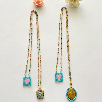 Quatro colares com pingentes coloridos e duas flores decorativas em fundo branco