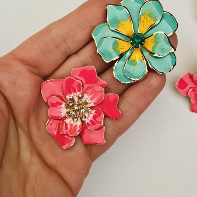 Broches florais azul turquesa e rosa na mão