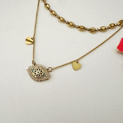 Duas pulseiras douradas com pingentes, uma com elos ovais e outra com pingentes de coração e olho decorativo.