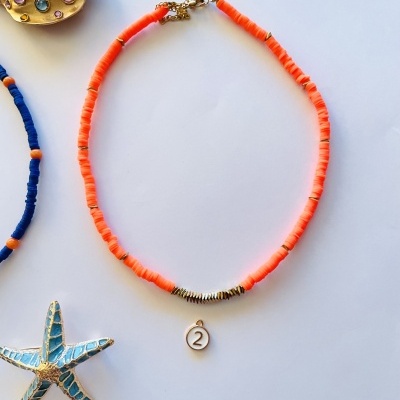 Colar cor de laranja com pingente número 2 e broches decorativos ao redor