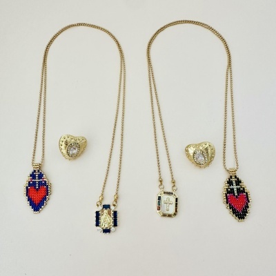 Três colares dourados com pendentes coloridos e dois pares de brincos dourados em forma de coração com pedra central.