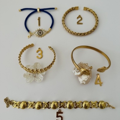 Cinco pulseiras douradas variadas numeradas sobre fundo branco