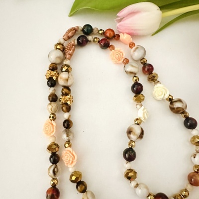 Colar de contas coloridas com flores em relevo e tulipa rosa no fundo branco