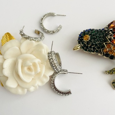 Três pares de brincos argola com cristais, flor branca decorativa e broche colorido em forma de inseto