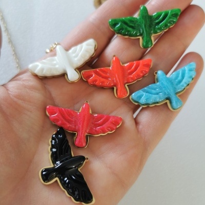 Pendentes coloridos em forma de pássaro sobre a palma da mão