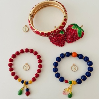 Cinco pulseiras coloridas numeradas sobre fundo branco, com contas e detalhes decorativos.