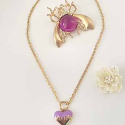 Colar com pendente de coração roxo e dourado, broche de inseto dourado com pedra roxa e flor branca em fundo branco