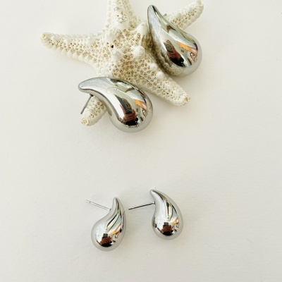 Conjunto de brincos prateados com formato de gota junto a estrela-do-mar decorativa