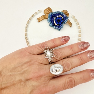 anel prateado com pérola e esferas, broche azul dourado, unhas glitter