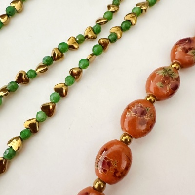 Dois colares de contas verde, dourado e alaranjado com detalhes florais