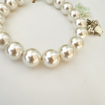 Colar de pérolas brancas com fecho decorativo em metal prateado.