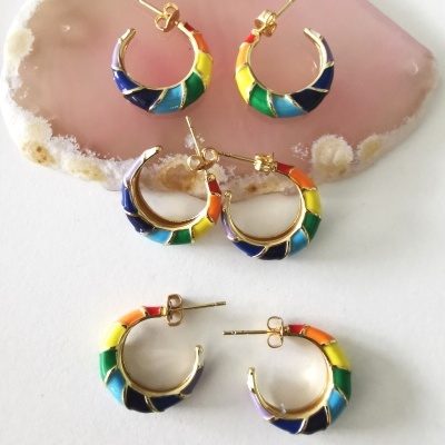 Brincos argola dourados com segmentos coloridos sobre fundo branco e pedra rosa