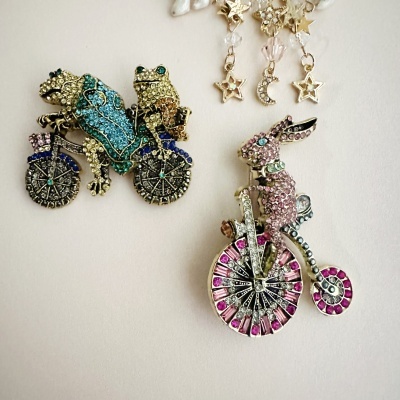 Broches brilhantes com sapos e coelho em bicicletas com pendentes de estrelas e lua