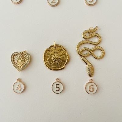 Peças de joalharia douradas com diferentes formas e números de 1 a 6.