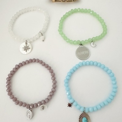 Pulseiras coloridas e broche de inseto com pedras sobre fundo branco