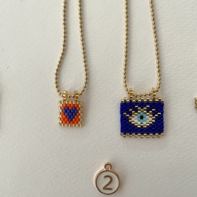 Duas colares com pendentes quadrados coloridos e marcador com o número 2.