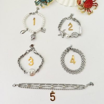 Cinco pulseiras prateadas numeradas com detalhes de pérolas e conchas
