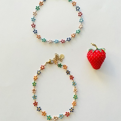 Dois colares de flores coloridas em fundo branco com pendente de morango