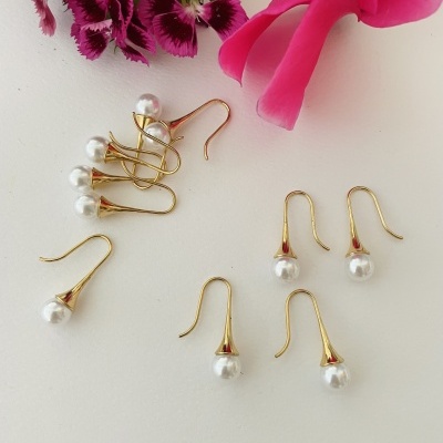 Brincos dourados com pérolas e flores cor-de-rosa e roxas ao fundo