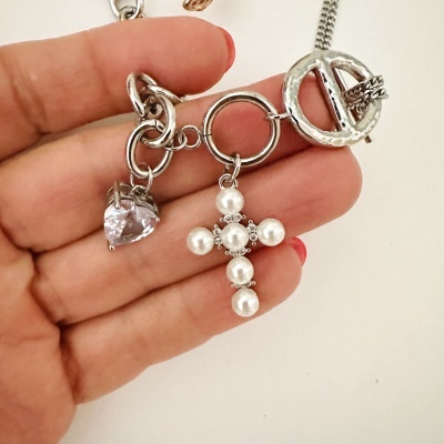 Colar prateado com pendentes de coração transparente e cruz de pérolas na mão